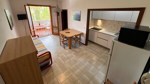 A compact kitchen with a dining area, a small table, and a refrigerator.