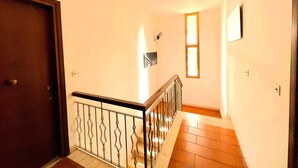 A staircase with a metal railing, a wooden door, and a wall-mounted light fixture.