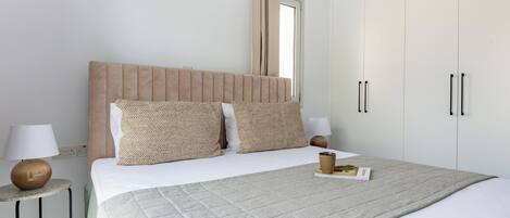 A bedroom with a bed, bedside tables, a wardrobe, and an air conditioning unit.