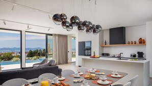 A modern hotel room with a dining area, breakfast setup, and a view of the mountains.