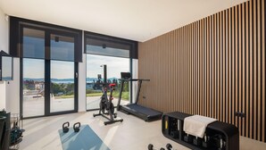 A modern home gym with a treadmill, kettlebells, and dumbbells.