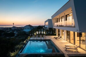 Un bâtiment moderne doté d’une piscine, d’un espace extérieur aménagé et de grandes fenêtres.