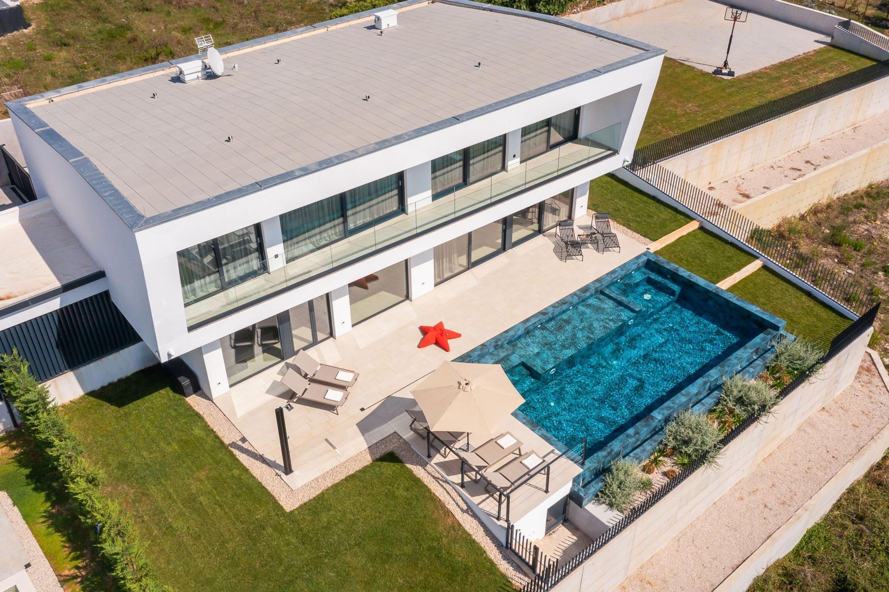 A modern two-story house with a swimming pool, outdoor seating, and a starfish decoration.