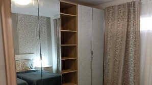 Un dormitorio con dos camas, un armario con espejo y una cortina.
