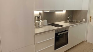 Una cocina moderna con armarios blancos, un lavamanos de acero inoxidable, un horno empotrado y un tostador.
