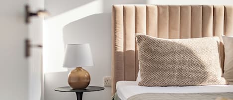 A bedroom with a bed, a bedside table with a lamp, and a window.