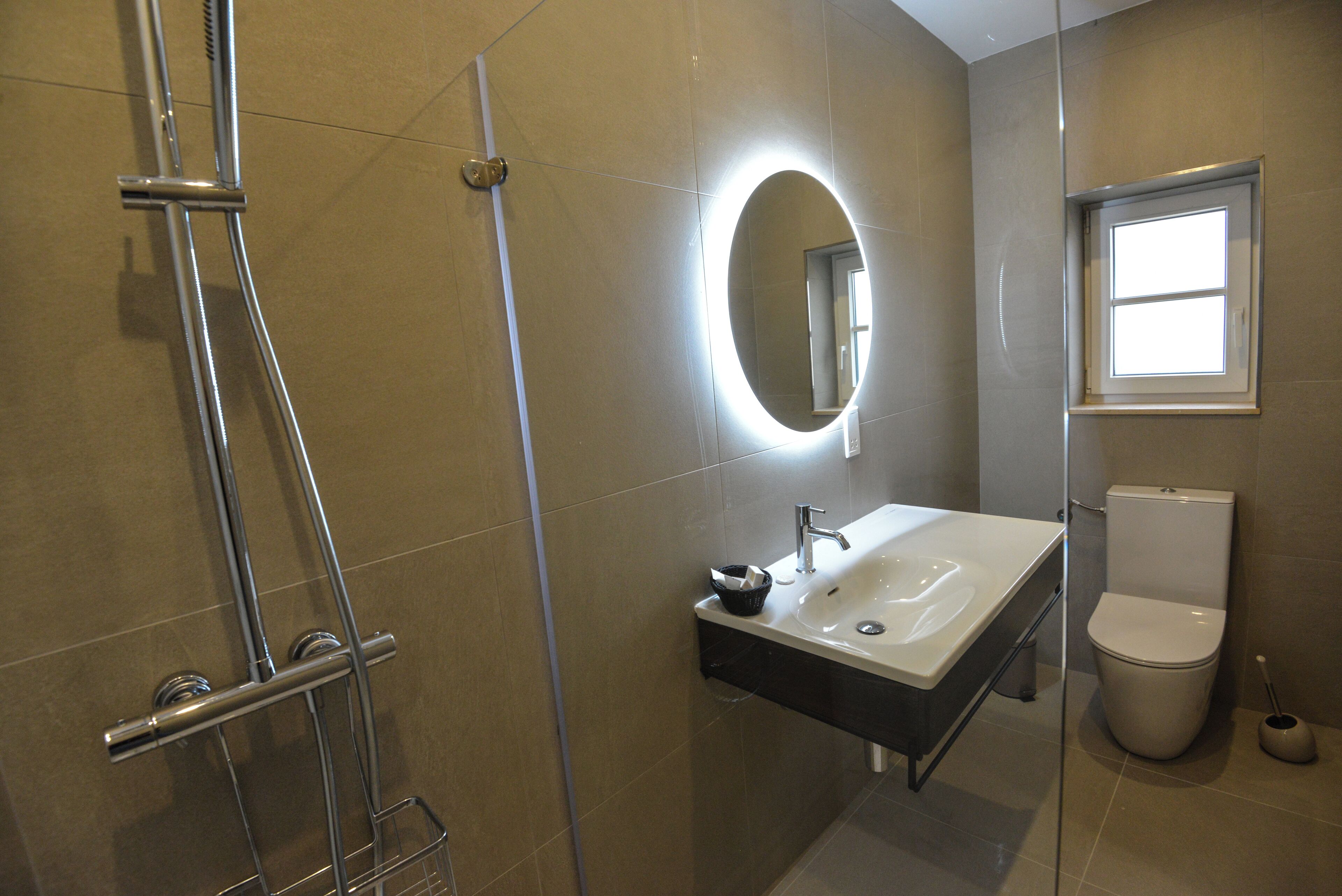 Une salle de bain moderne avec une douche à parois de verre, un meuble-lavabo avec un miroir et des toilettes.