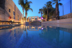 Una piscina con vistas despejadas a la arquitectura circundante, incluyendo un edificio de piedra y palmeras.