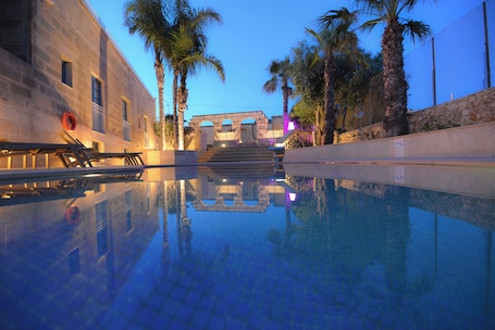 Una piscina al aire libre, sombrillas, sillones reclinables de piscina