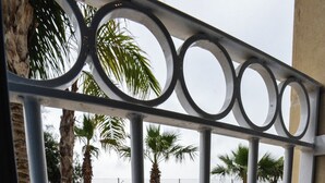Ein Poolbereich mit Steinboden, Palmen und einem Metallgeländer.