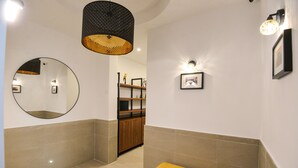 Ein modernes Badezimmer mit einem runden Spiegel, einer Sitzbank und einem Ablagebereich für Toilettenartikel.