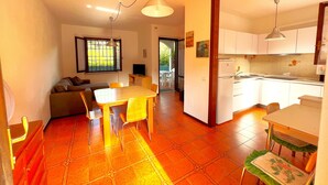A compact living space with a dining area, kitchen, and a seating area with a TV. - Paguro (Grosseto)
