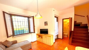 A living room with a sofa, TV, and a dining area with a table. - Paguro (Grosseto)