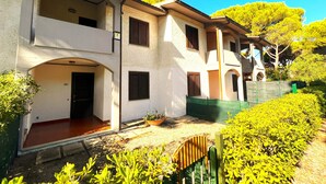 A two-story building with a covered entrance, multiple windows, and a small garden area. - Paguro (Grosseto)