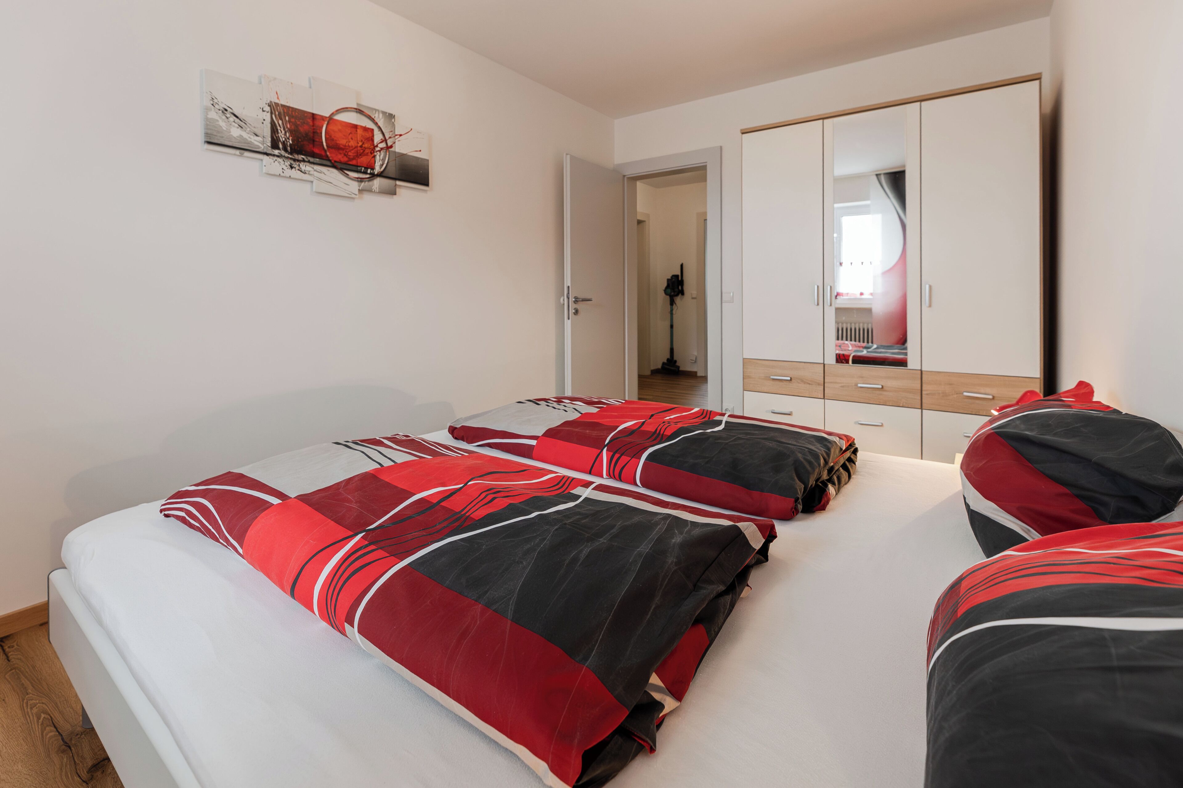 Un dormitorio con cama, armario y espejo.