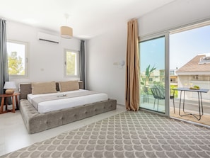 A modern bedroom with a large bed, a bedside table, a lamp, and a view of the outside balcony. - Sanders Cruise - Spacious Studio Apt With Balcony (Limassol)
