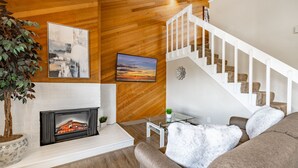 Ein modernes Wohnzimmer mit Kamin, Holzböden, einer Treppe und einem Sofa.