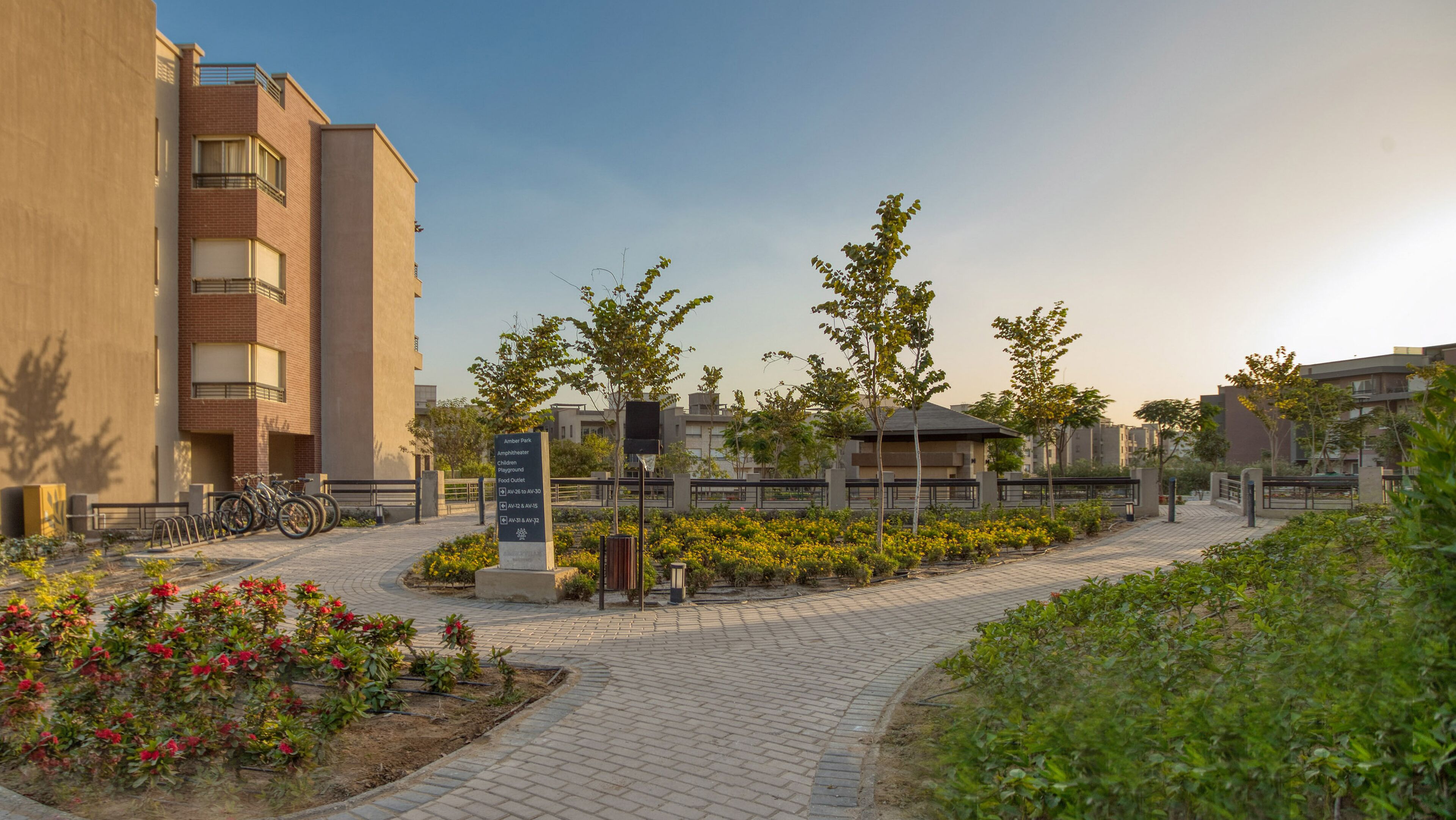 Área residencial com calçada pavimentada, um sinalizador indicando os serviços e um edifício com varandas.