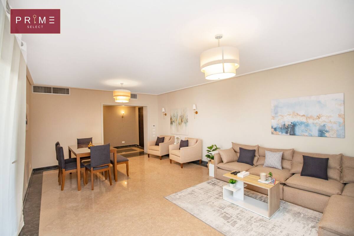 A modern living room with a dining area, beige sofas, a coffee table, and a painting on the wall.