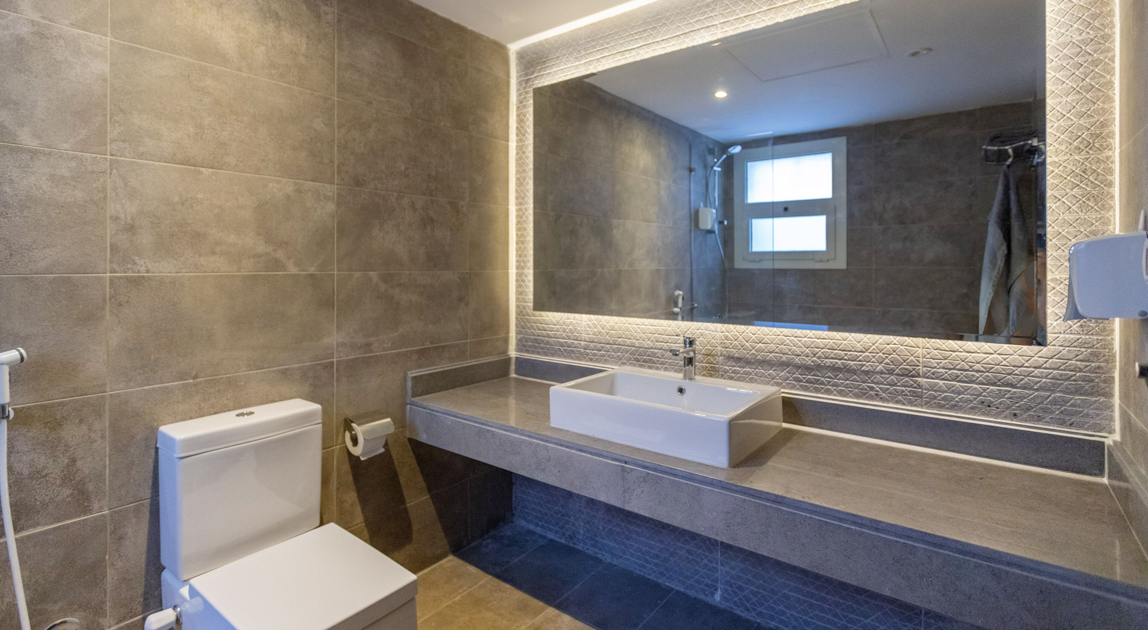 Ein modernes Badezimmer mit zwei Waschbecken, einer Toilette und einem großen Spiegel.