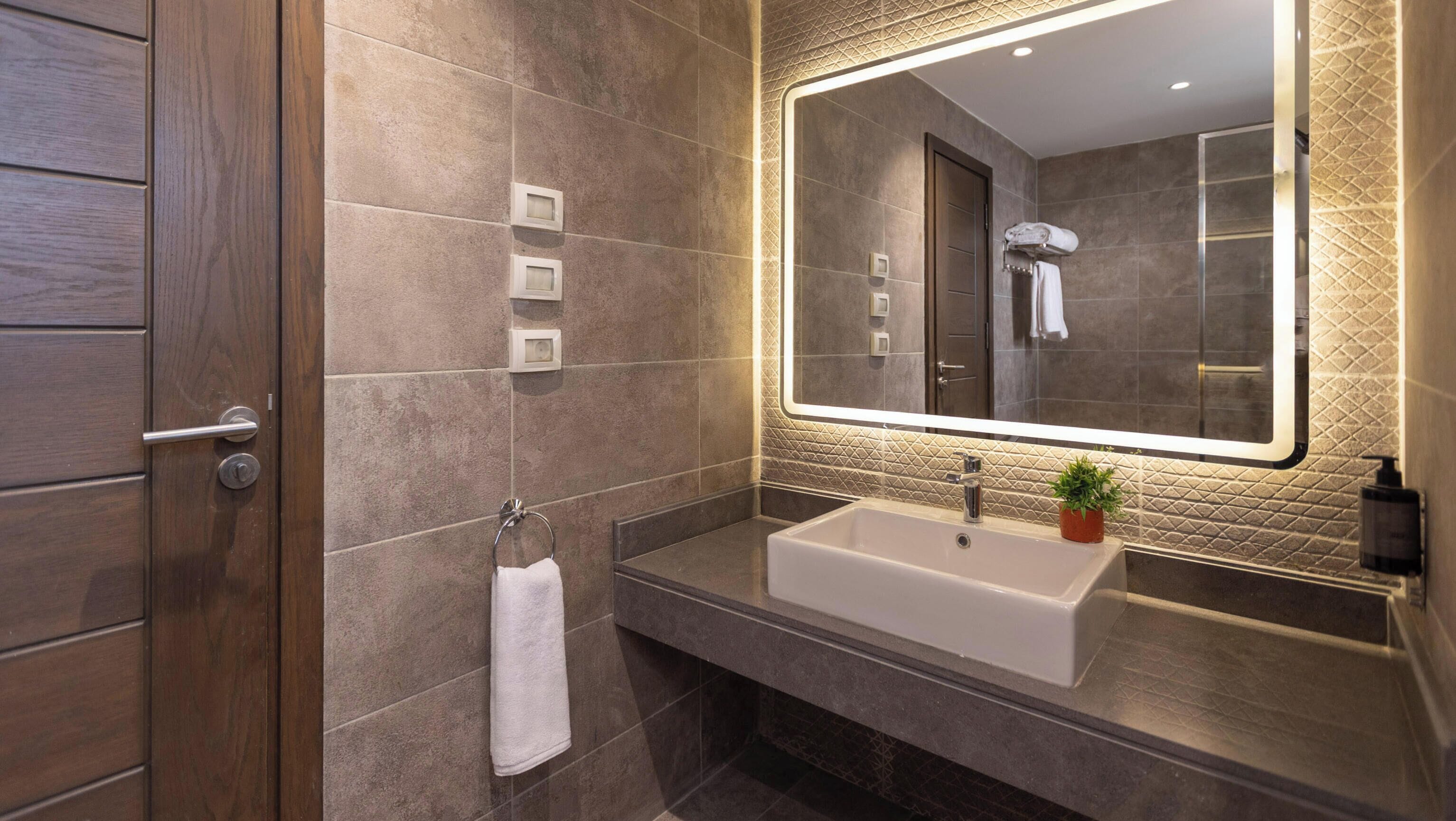 A modern bathroom with a large mirror, a sink, and a towel rack.