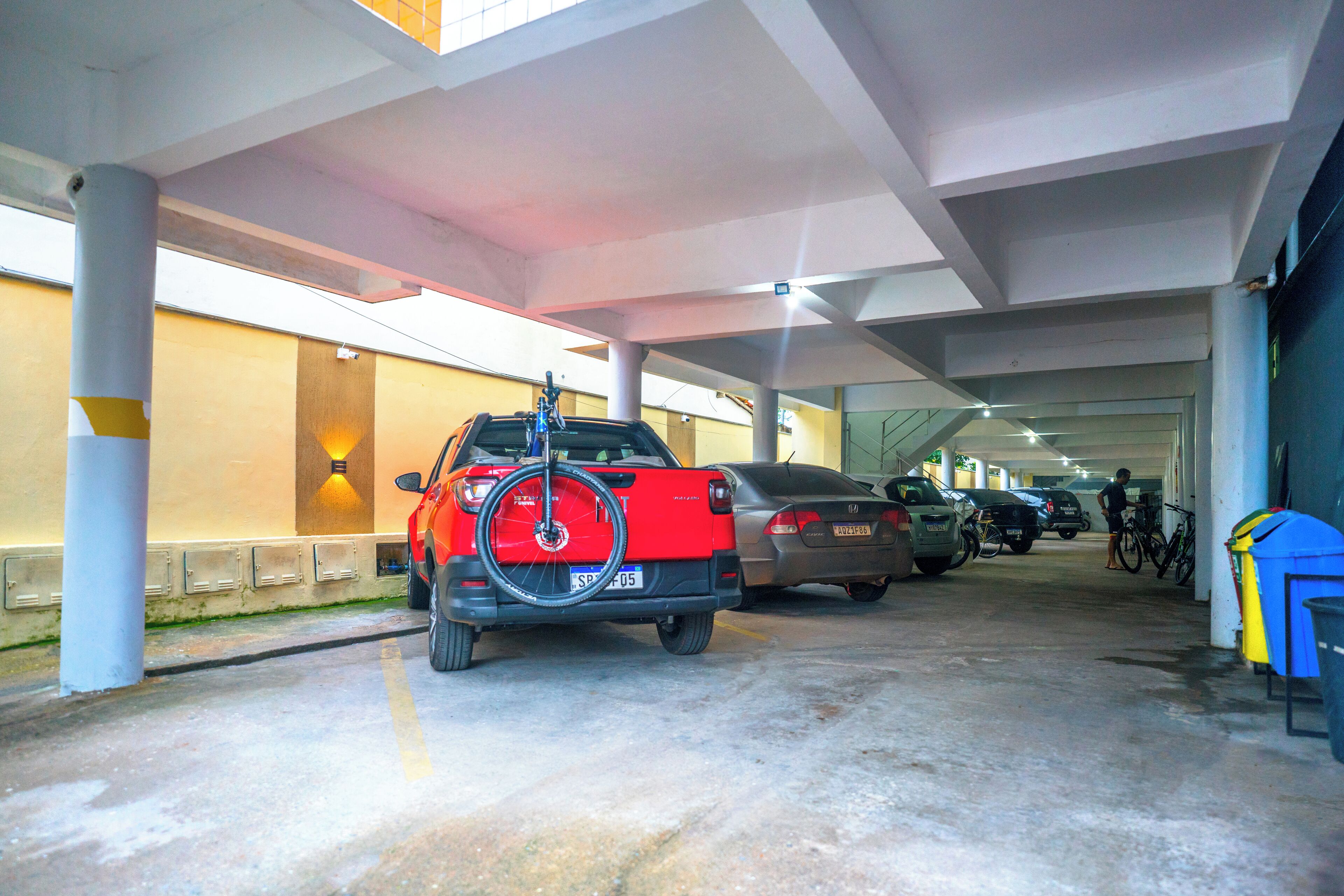 A parking garage with cars and a bicycle rack.