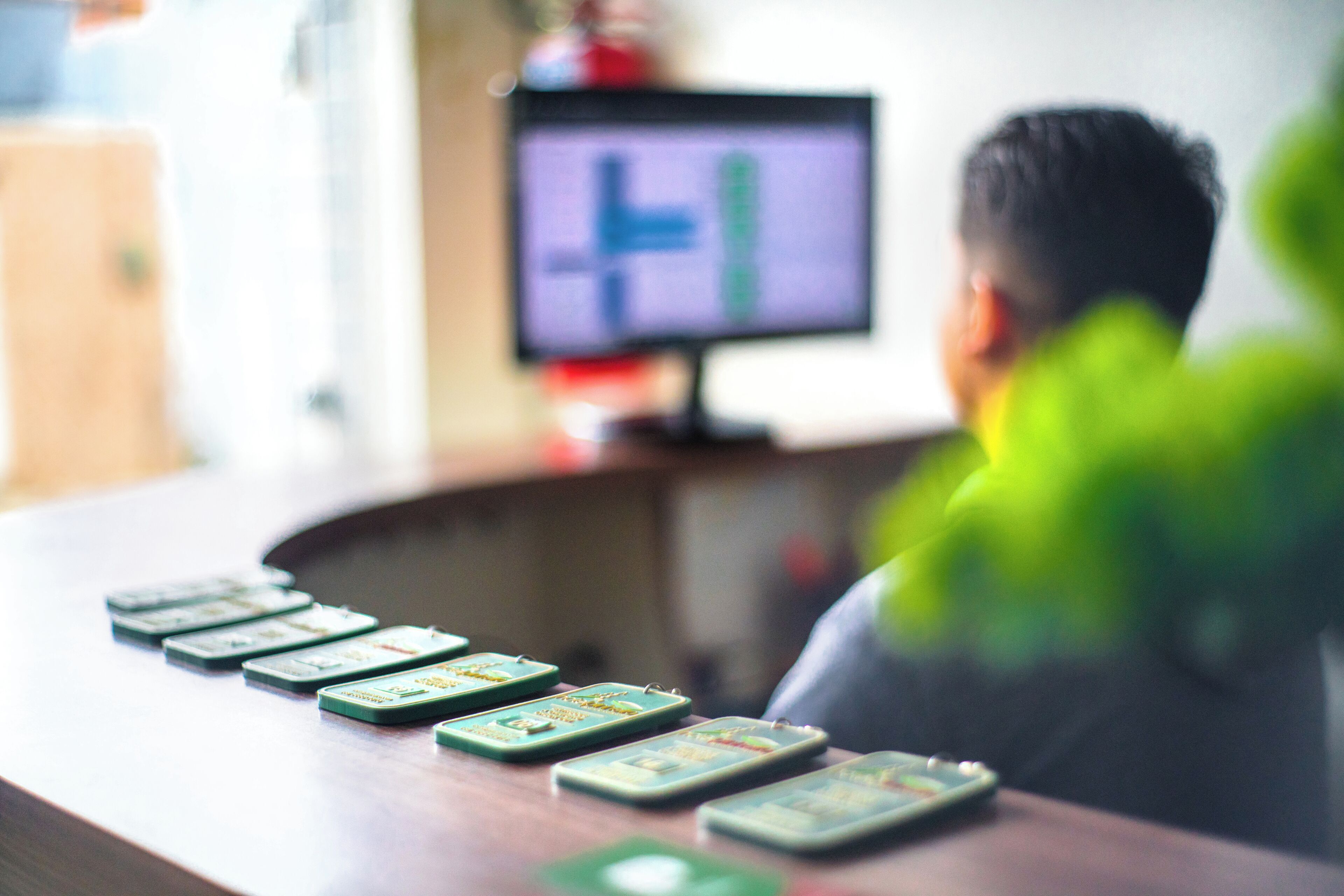 Un mostrador de recepción de madera con un monitor de computadora y varios portatarjetas verdes.