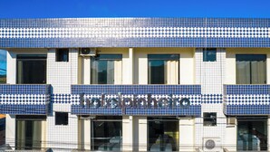 A hotel facade with a blue and white checkered tile pattern, large windows, and a visible air conditioning unit. - Hotel Pinheiro (Ibiapina)