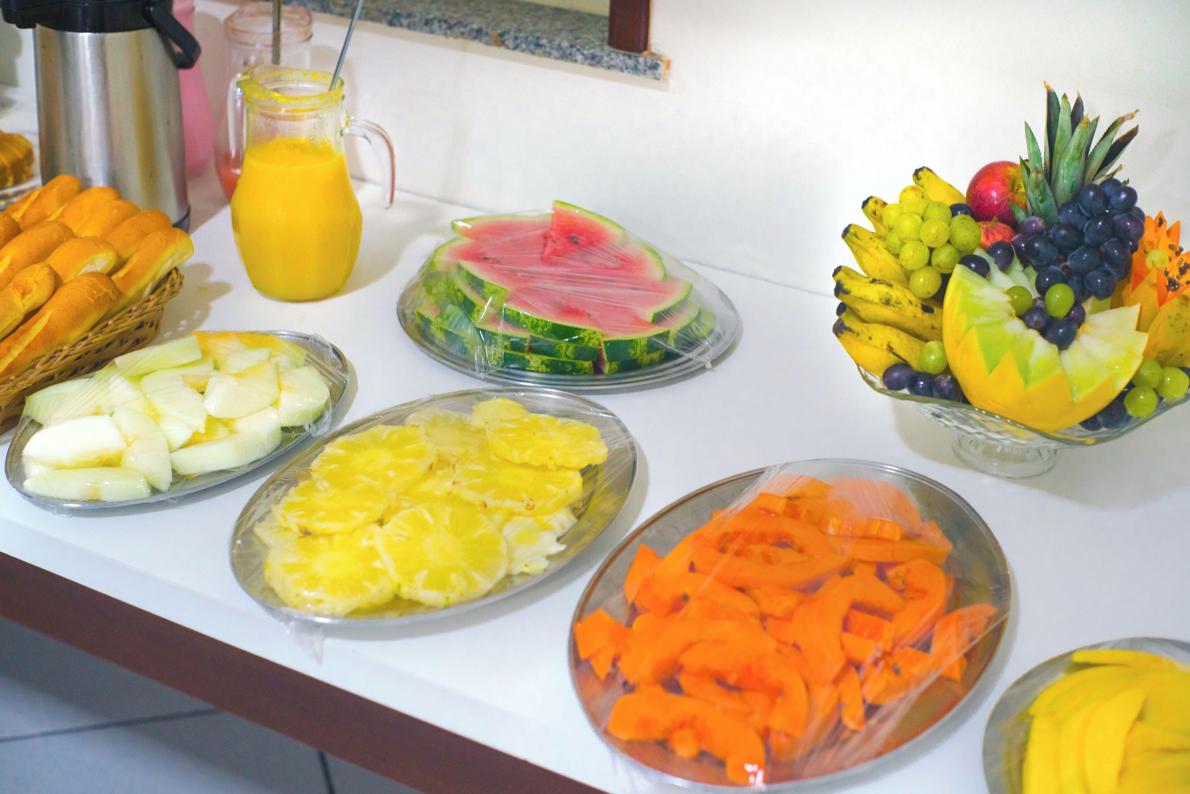 Un bufé con varias frutas y una cafetera.