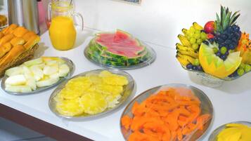 Un bufé con varias frutas y una cafetera.