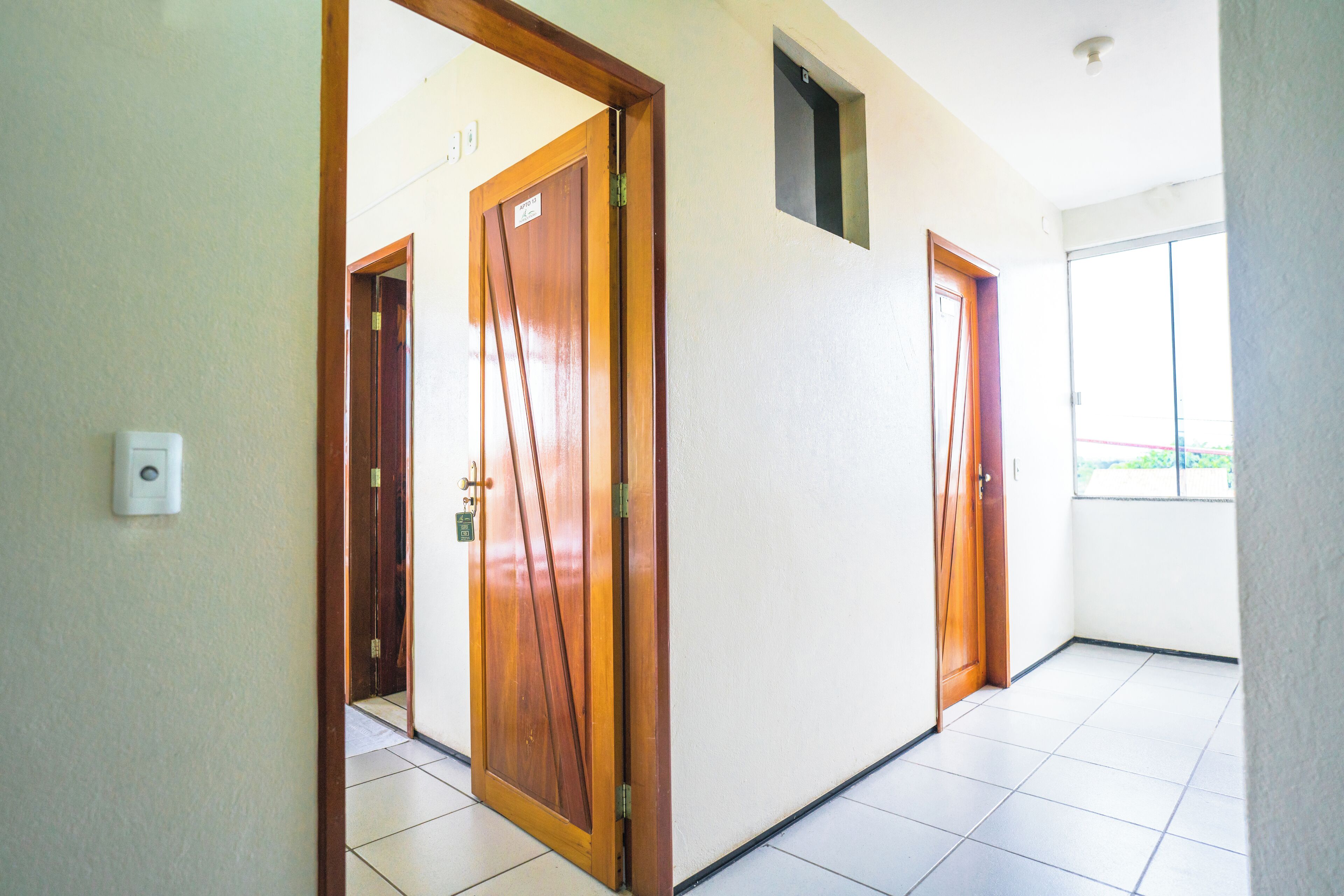 A hallway with wooden doors, a visible intercom, and a window with a view.