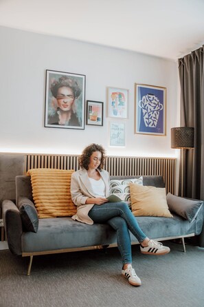 A modern living room with a grey sofa, a wooden headboard, and a floor lamp.