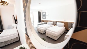 Et hotelværelse med to senge, et skrivebord, en stol og et spejl der viser rummet.