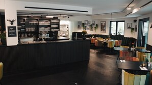 En restaurant med barområde, flere siddepladser og forskellige bordopstillinger.