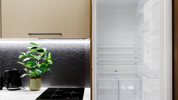 Eine Küche mit Marmorarbeitsplatte, einer schwarzen Kaffeemaschine, einer grünen Pflanze und einem modernen Kühlschrank.