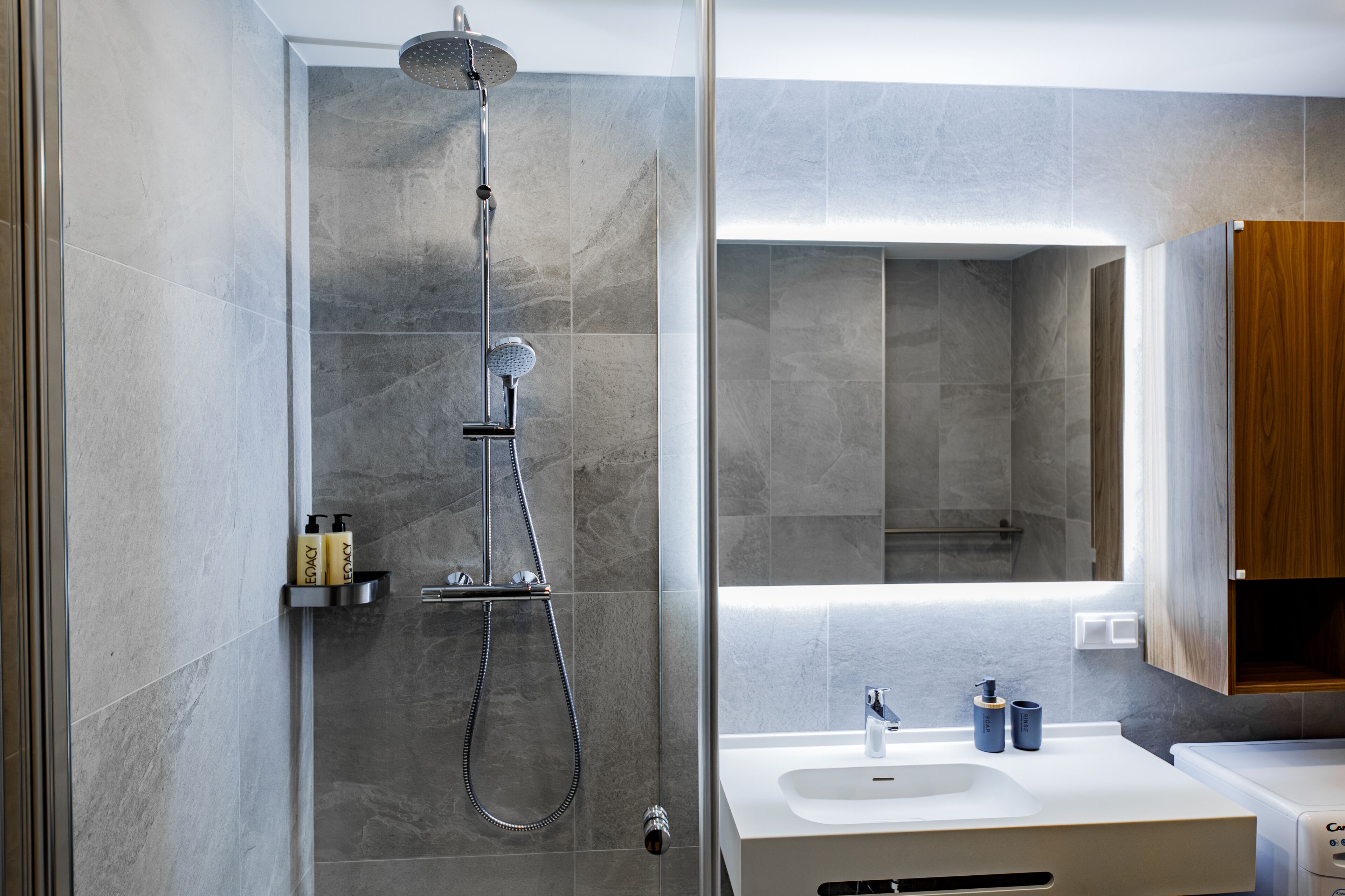 Une salle de bain moderne avec une douche, un lavabo et un meuble en bois.