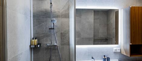 Une salle de bain moderne avec une douche, un lavabo et un meuble en bois.