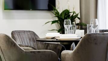 Un comedor moderno con una mesa redonda, cuatro sillas tapizadas y un televisor de pantalla plana montado en la pared.