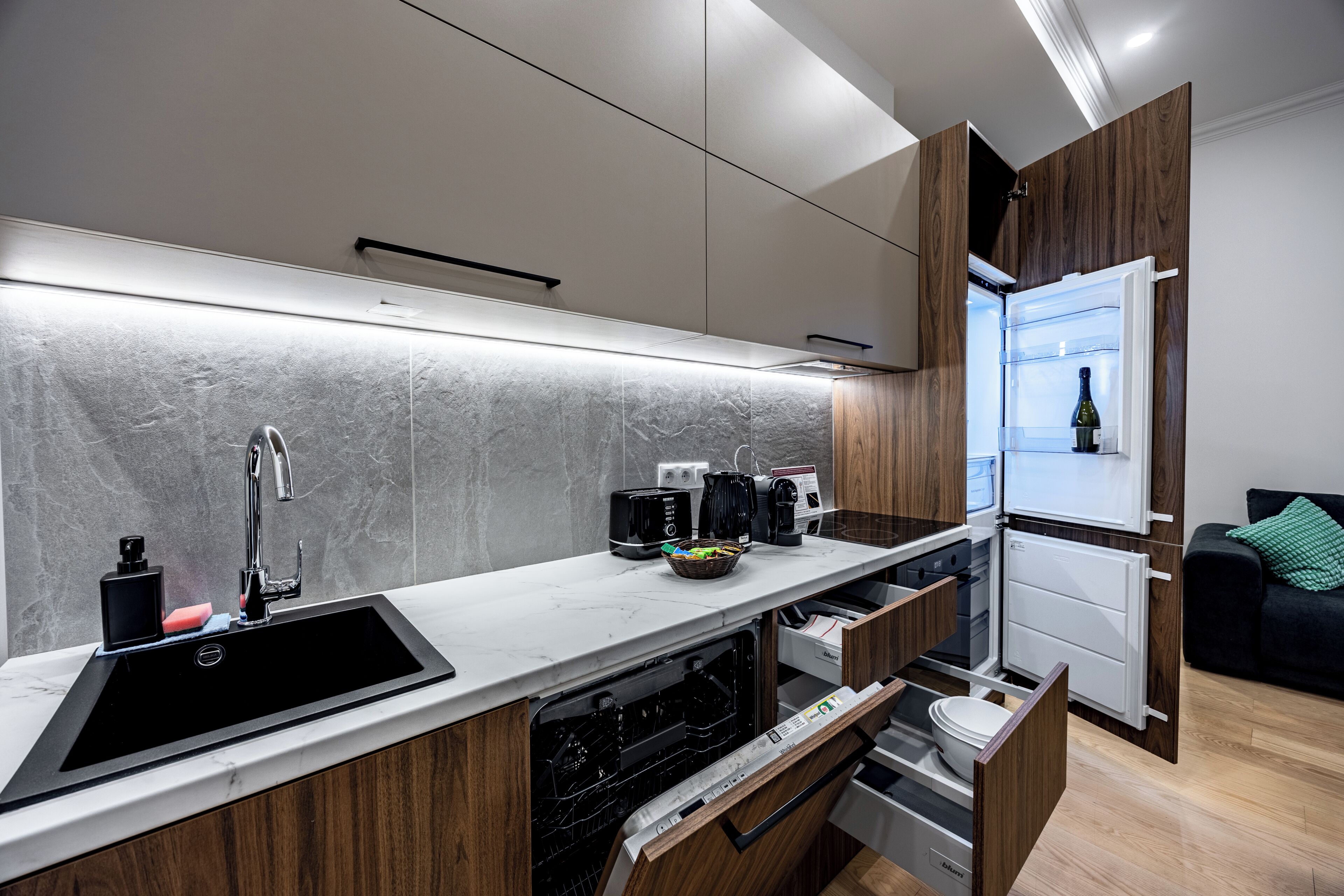 A modern kitchen with a built-in dishwasher, a sink, a coffee machine, and a refrigerator.