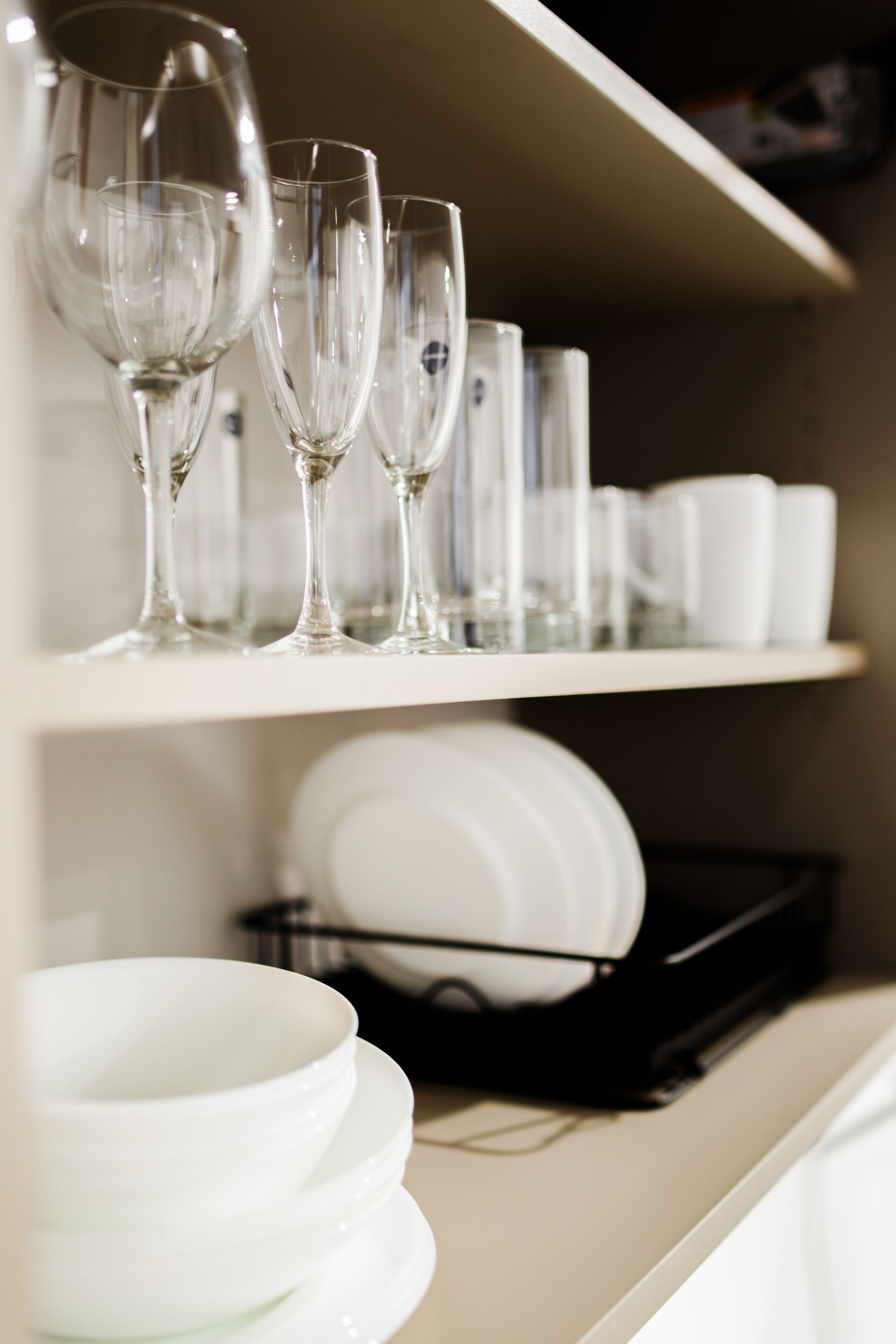 Uma estante com copos de vinho e tigelas brancas.