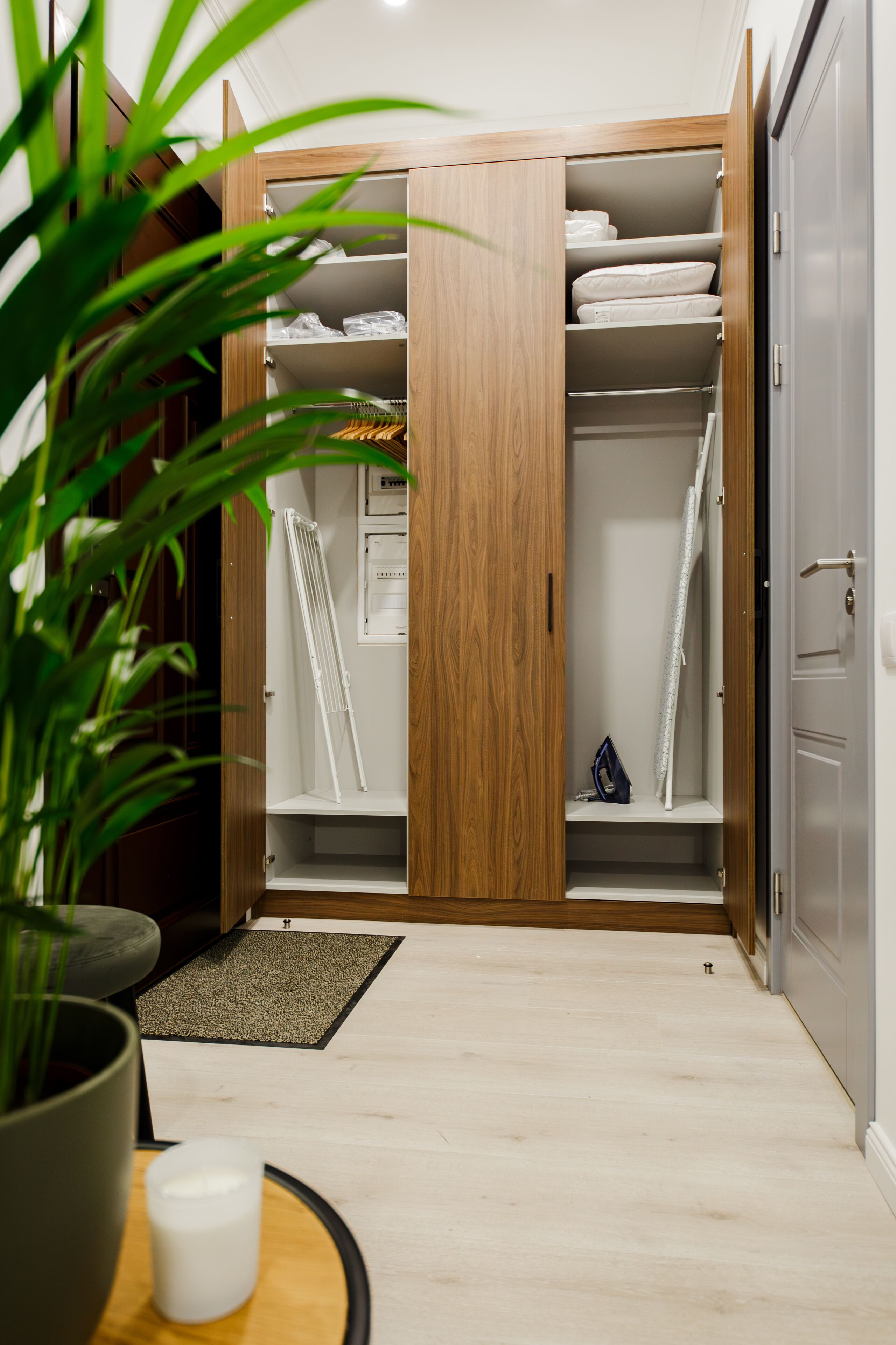 A wooden wardrobe with multiple shelves, a hanging rack, and a small shelf with a blue bag.