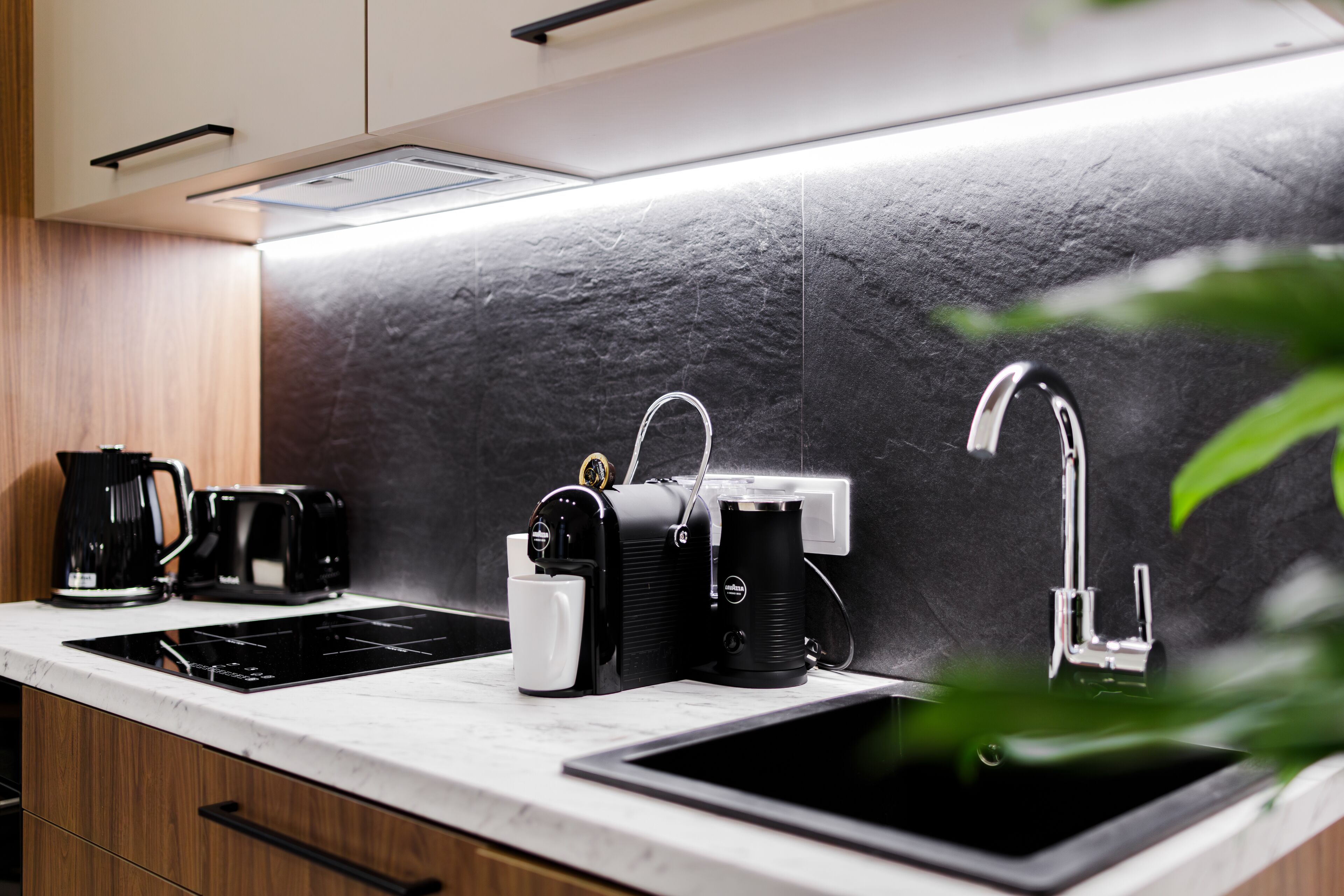 Une cuisine moderne avec un plan de travail noir et blanc, une machine à café, un grille-pain et un évier.