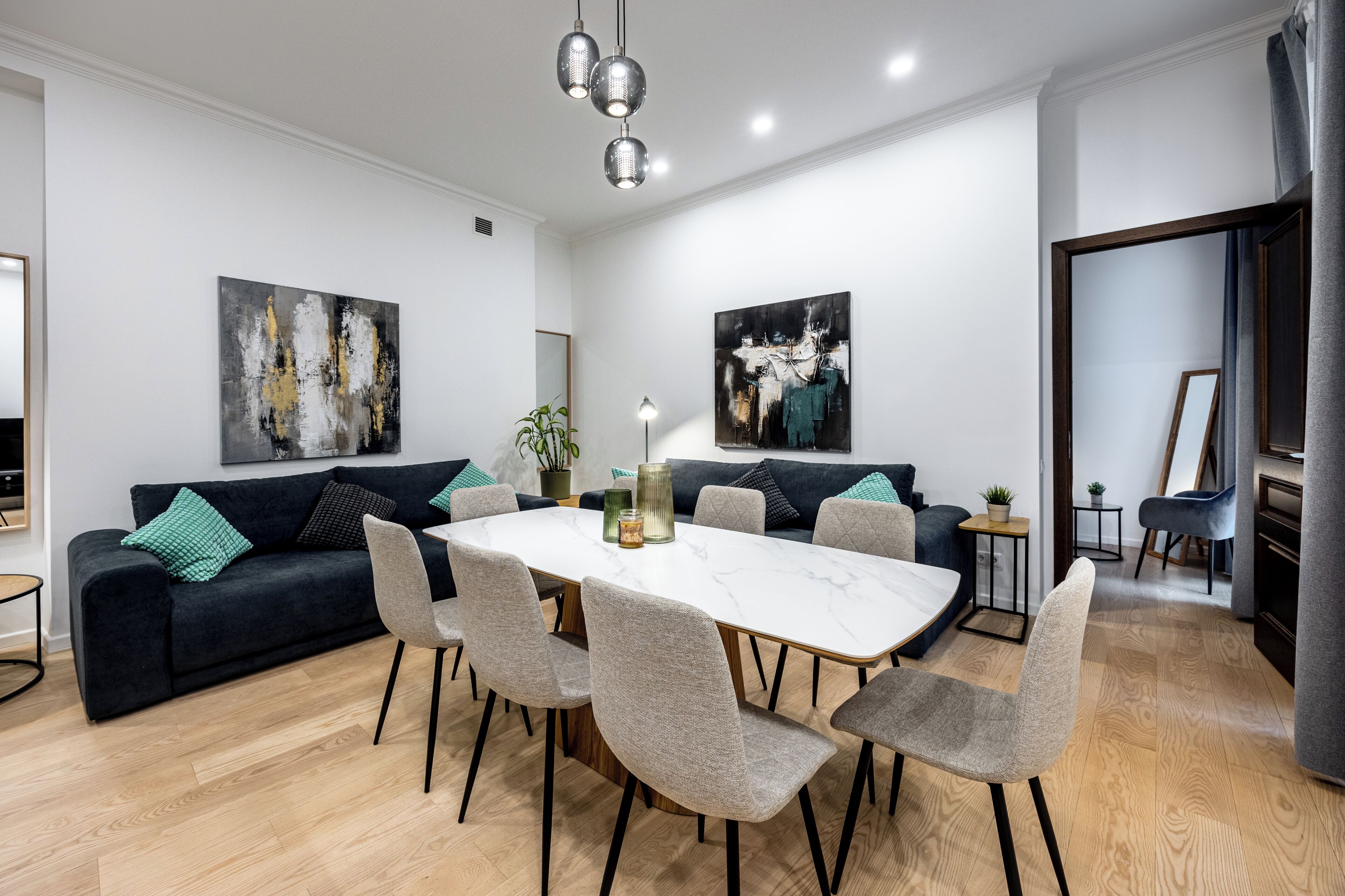 Un comedor moderno con una mesa blanca, sillas grises y sofás negros y grises.