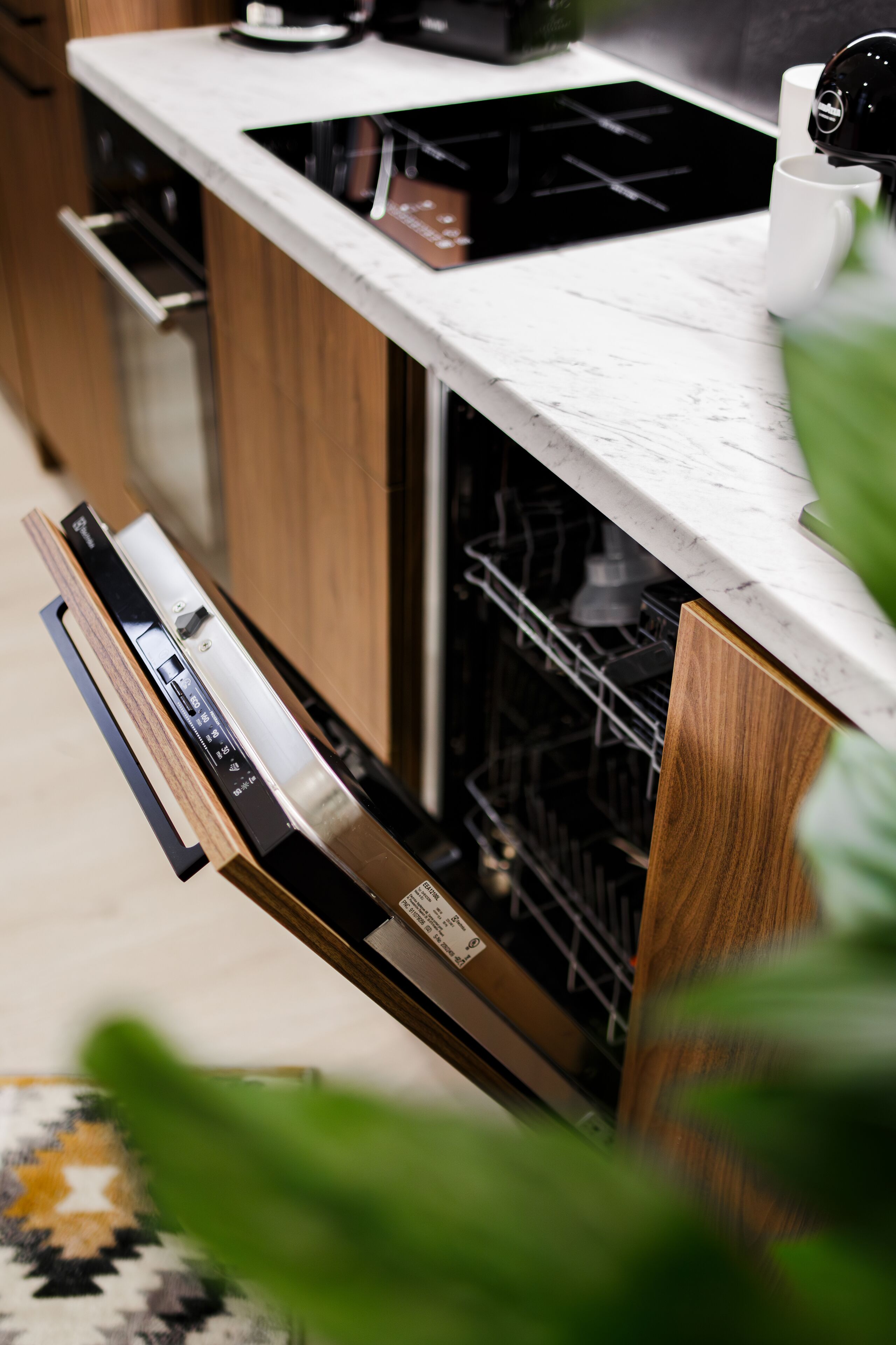 A kitchen with a dishwasher, a stove, and wooden cabinets.