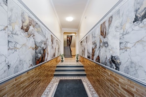 A marble-floored hallway with a staircase, brick walls, and a black carpet. - RigaApartment E22, Self Check-in Aparthotel, near Old Town (Riga)