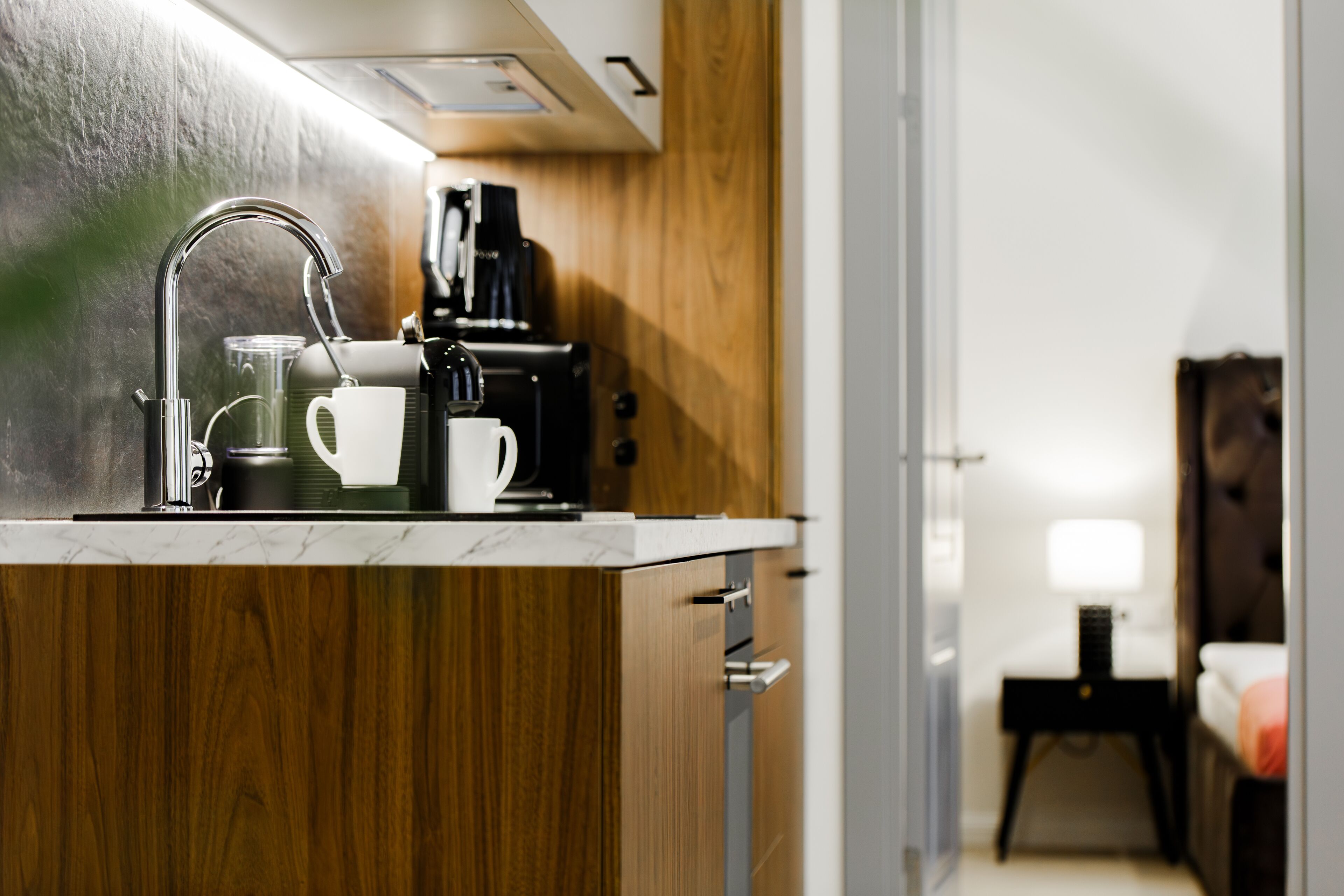A modern kitchen with a stainless steel sink, a coffee maker, and a glass carafe.