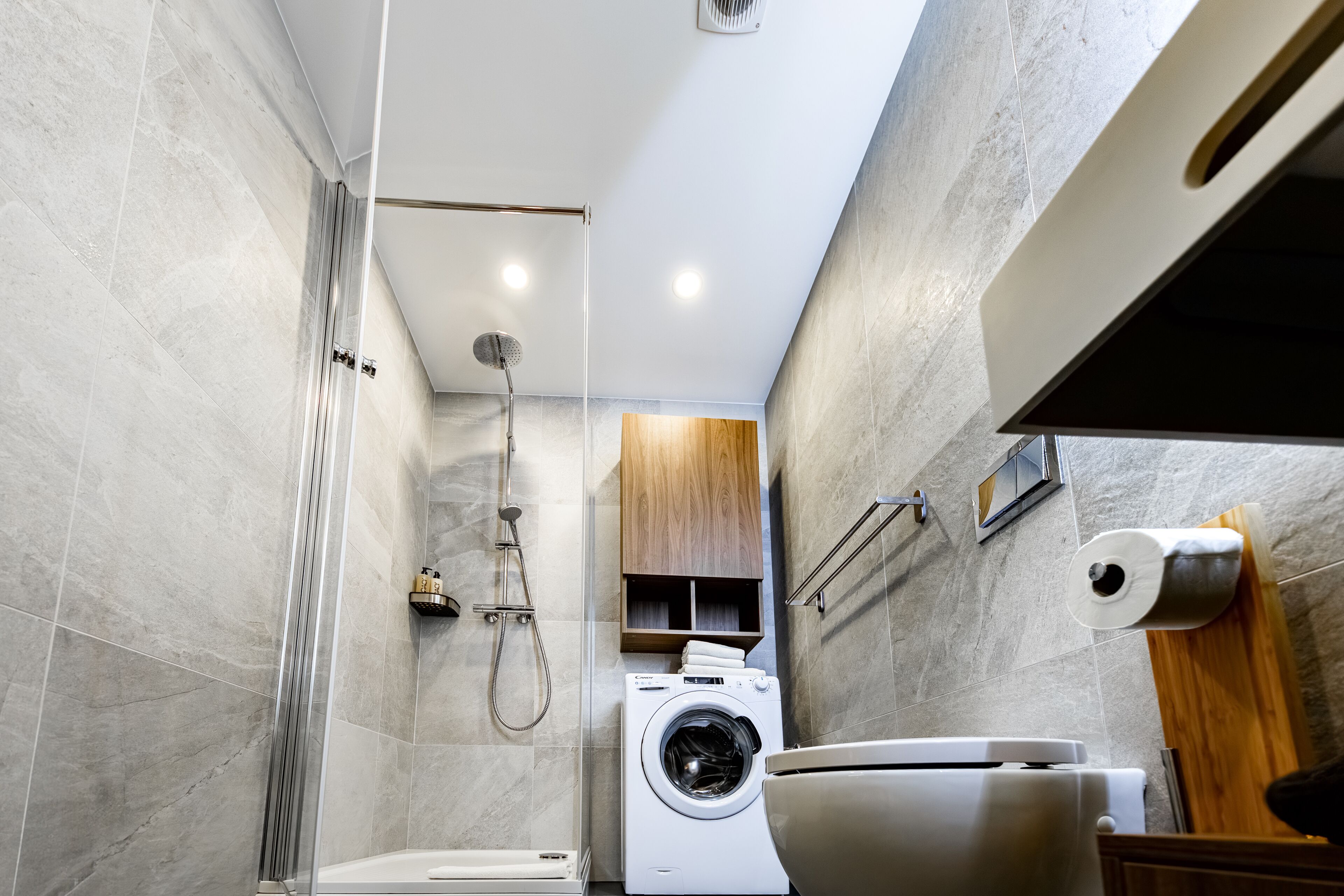 Ein kleines Badezimmer mit Dusche, Toilette und Waschmaschine.