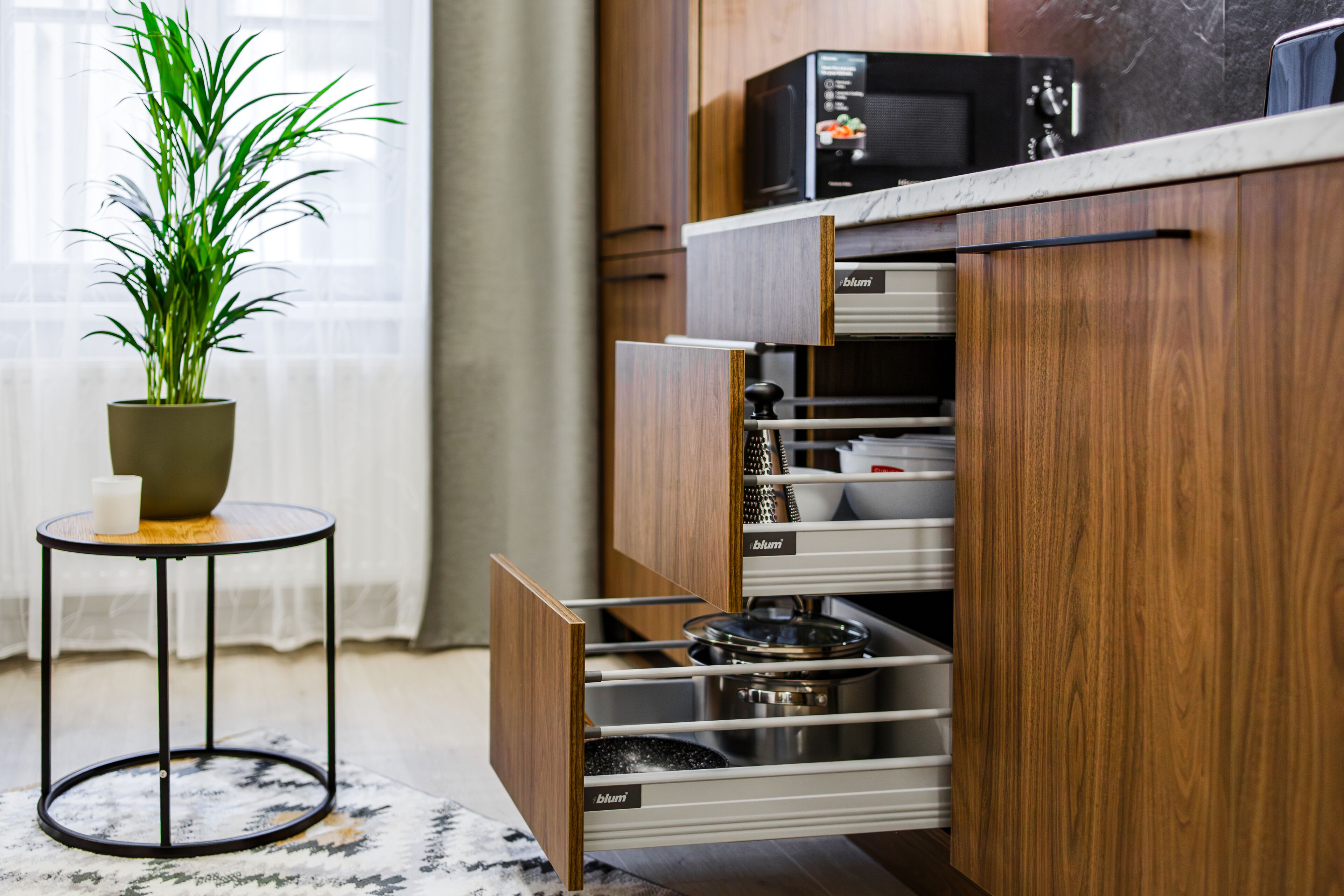 A kitchen with wooden cabinets, a microwave, and a potted plant on a small table.