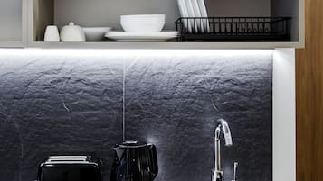 A kitchen with a marble countertop, a black coffee maker, a toaster, and a sink with a modern faucet.