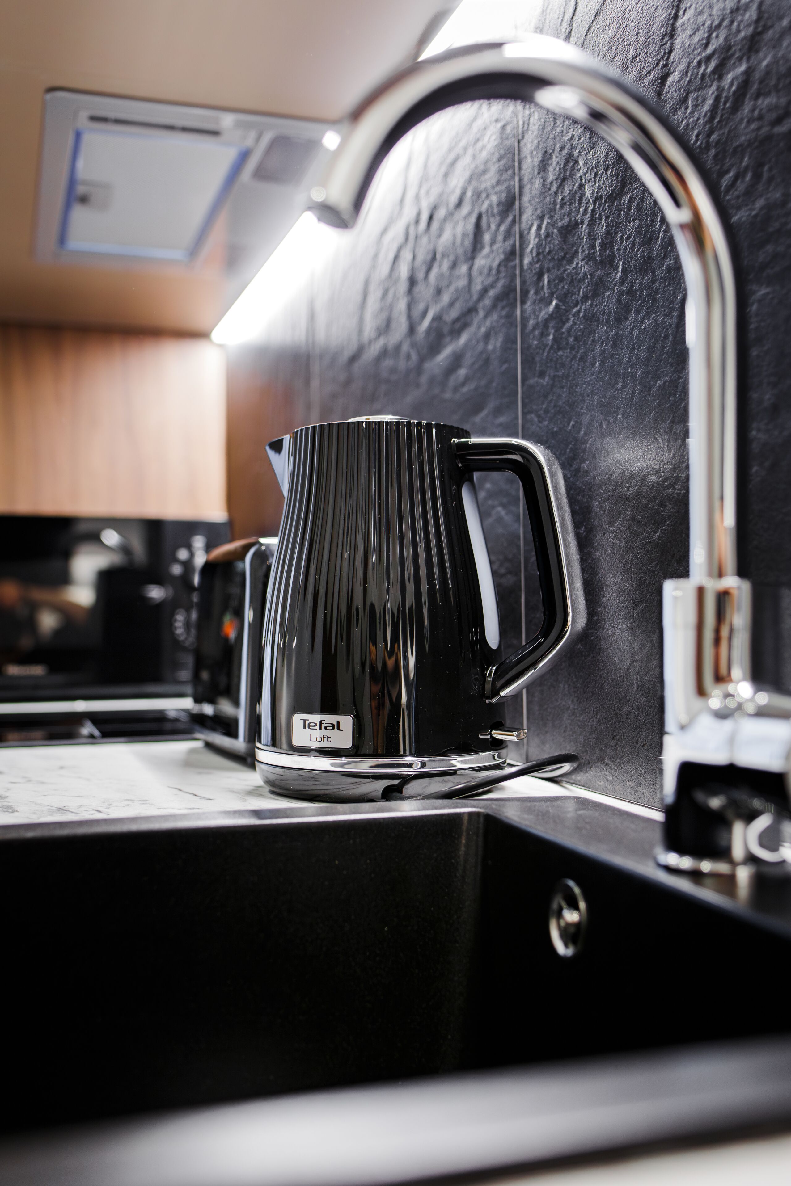 A black coffee maker with a handle on a kitchen counter.